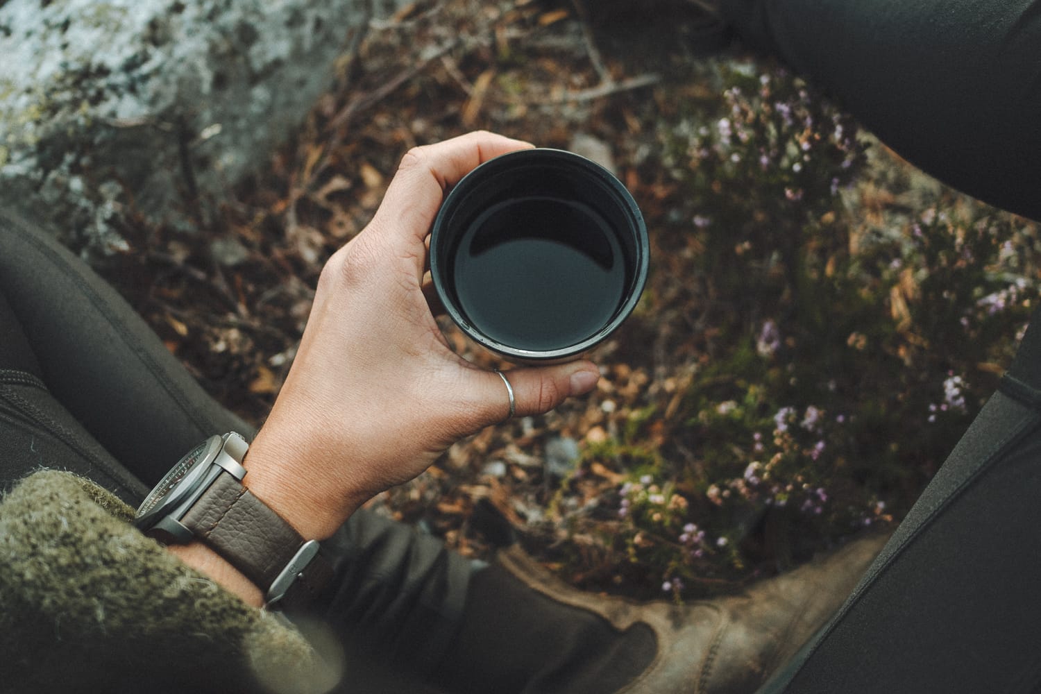 a hand holding a cup of coffee outside