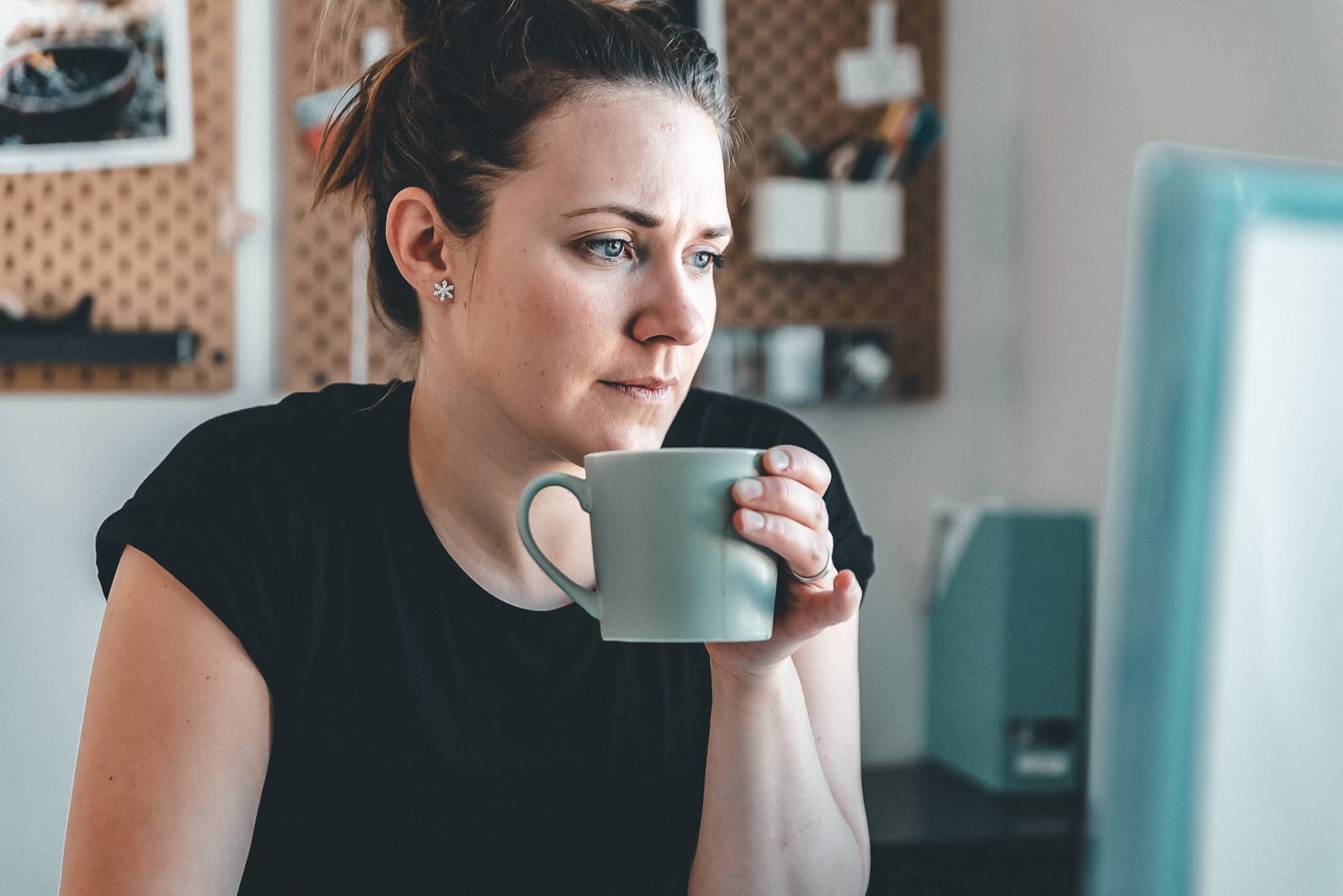 Woman drinking coffee infront of her computer