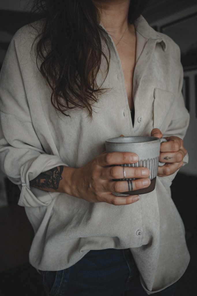 woman with tattoos holding coffee cup
